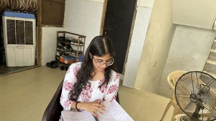 सुरभि सिंह अपने एक कमरे वाले अपार्टमेंट के बाहर नोट्स देखते हुए | फोटो: नूतन शर्मा/दिप्रिंट