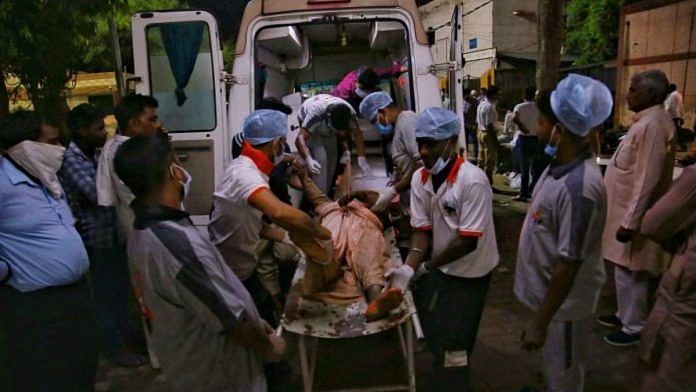 हाथरस के बागला अस्पताल के कर्मचारी शवों को पोस्टमार्टम के लिए एंबुलेंस में भेजने के लिए तेज़ी से काम कर रहे हैं | फोटो: मनीषा मोंडल/दिप्रिंट